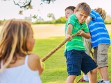 Kinder spielen Tauziehen draußen im Garten